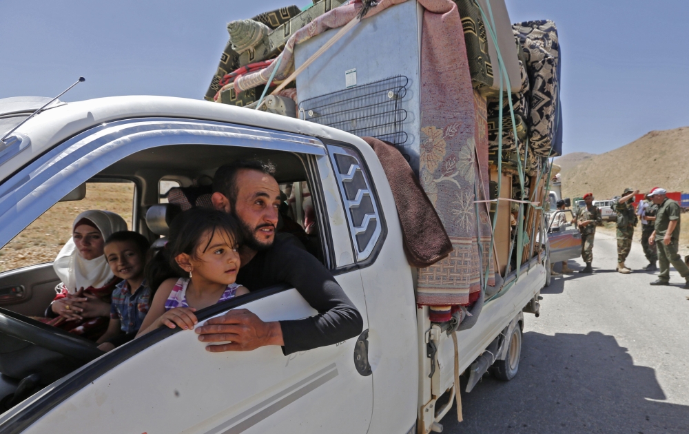 Syrian refugees arriving in their country from the eastern Lebanese border town of Arsal, drive through the crossing of al-Zamrani between the two countries on June 28, 2018.  AFP / Louai Beshara
