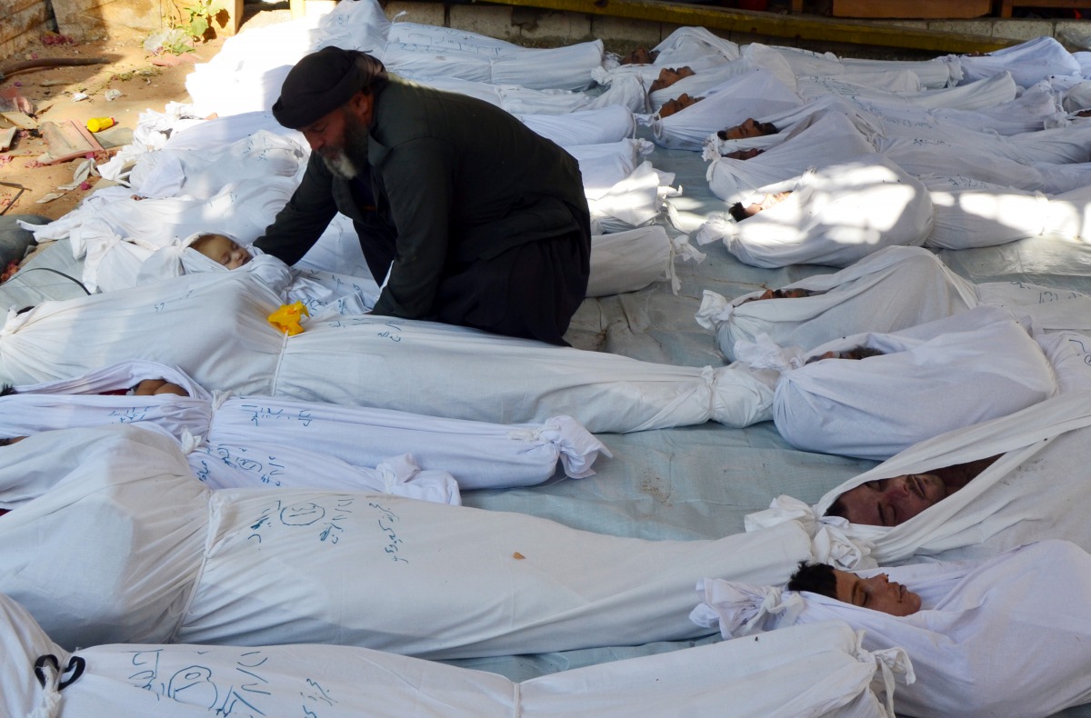 A man holds the body of a dead child among bodies of people activists say were killed by nerve gas in the Ghouta region in the Duma neighbourhood, August 21, 2013. (Reuters / Bassam Khabieh) 