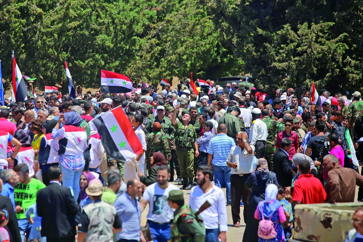 Syrians wave the national flag in the town of Quneitra in the Syrian Golan Heights on July 27, 2018. The town was almost completely destroyed by departing Israeli soldiers in 1974 after seven years of occupation. AFP / Youssef Karwashan