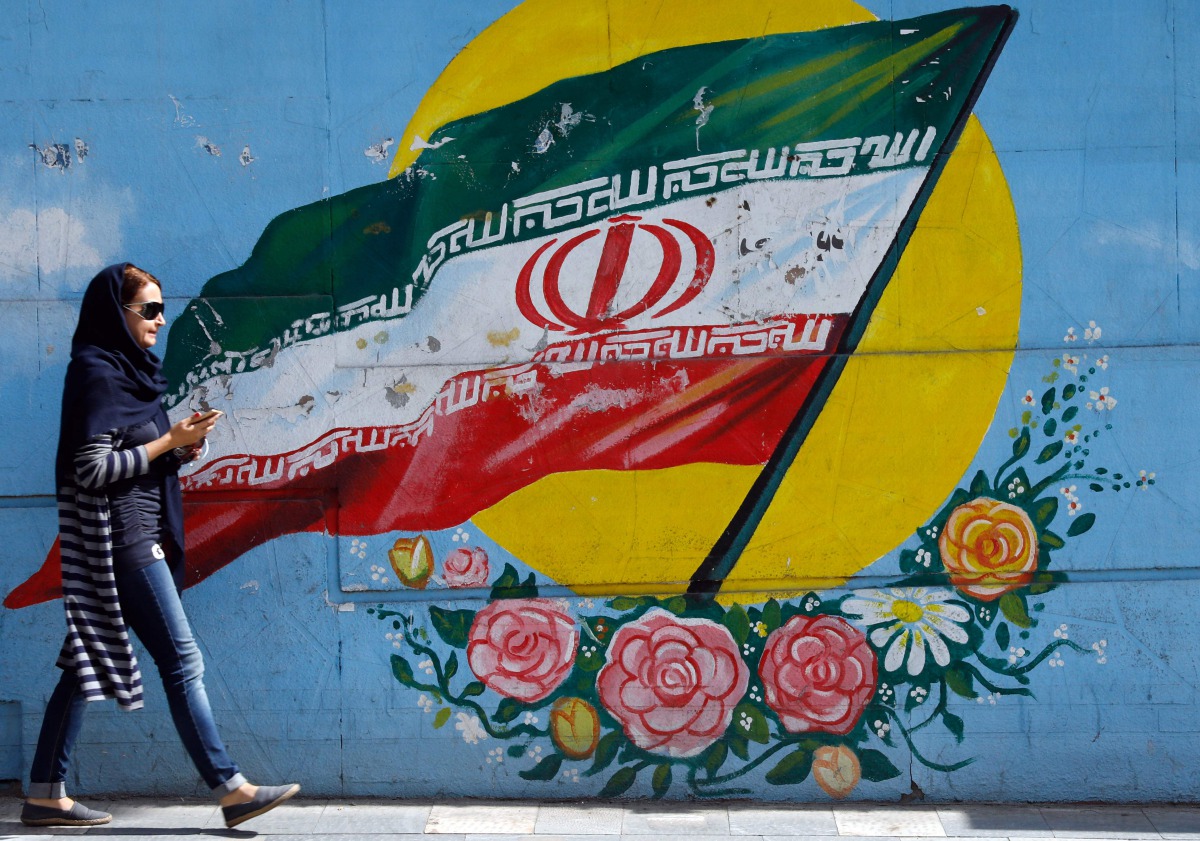An Iranian woman walks past a mural of the Iranian flag in Tehran on October 14, 2017. (AFP) 
