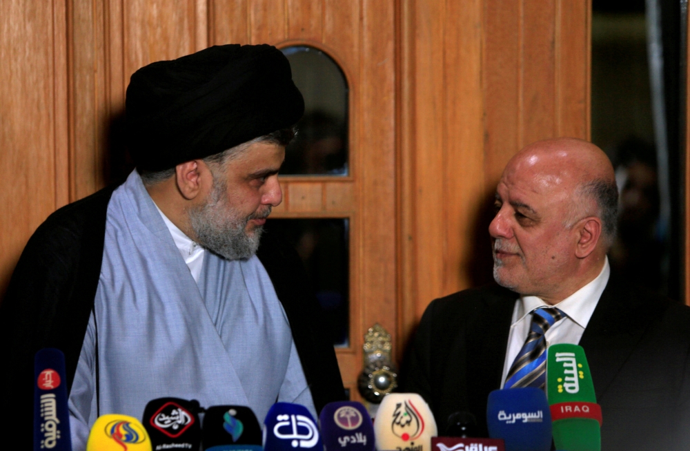 FILE PHOTO: Iraqi Shi'ite cleric Moqtada al-Sadr looks at Iraqi Prime Minister Haider al-Abadi during a news conference in Najaf, Iraq June 23, 2018. Reuters/Alaa al-Marjani 