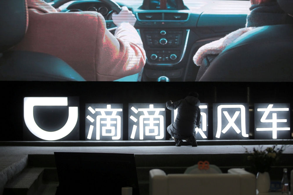 File photo of a man is seen in front of a DiDi sign before a promotional event of its Hitch service for the Spring festival travel rush, in Beijing, China January 24, 2018. REUTERS/Stringer/File Photo