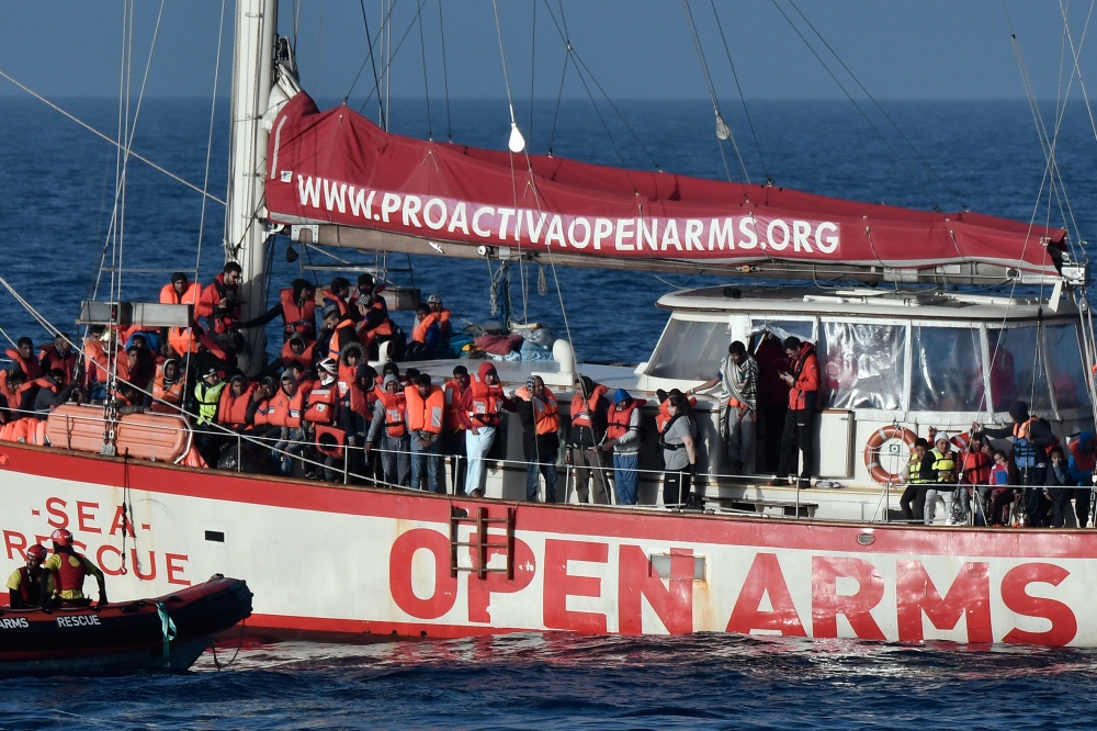 (FILES) In this file photo taken on May 7, 2018 rescued migrants stand onboard the Open Arms Yacht of Spanish based non-governmental organisation Proactiva, some 35 nautical miles off Libya coast.  AFP / LOUISA GOULIAMAKI