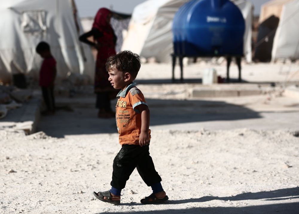 A child walks in front of tents at a camp for the displaced from the rebel-held Syrian province of Idlib, at the village of al-Ghadfa, southeast of the province on September 2, 2018. AFP / Nazeer AL-KHATIB
