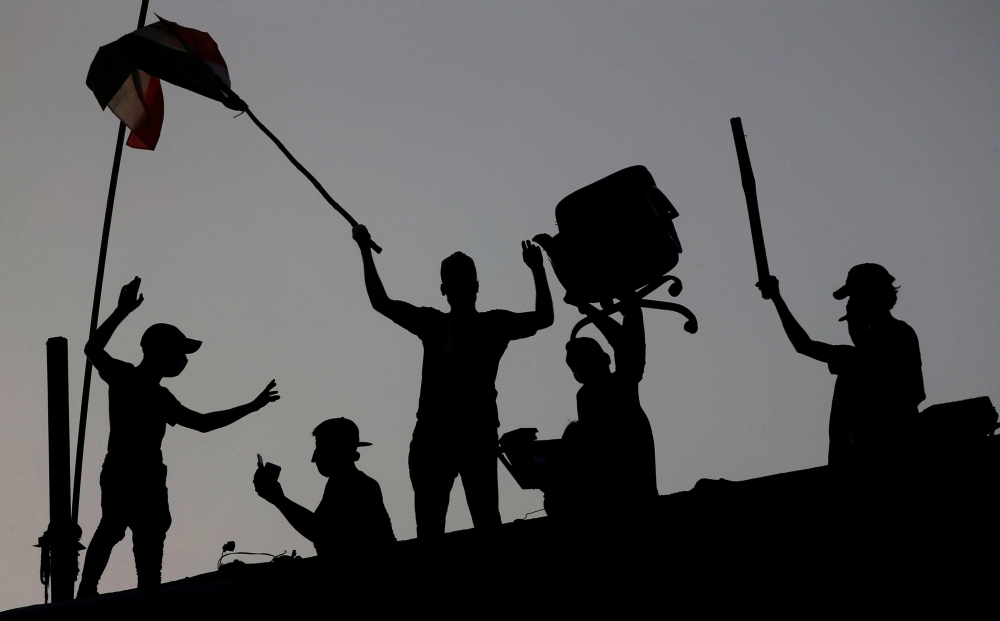 Iraqi protesters stand on concrete blast walls during an anti-government protest near the building of the government office in Basra, Iraq September 7, 2018. REUTERS/Alaa al-Marjani