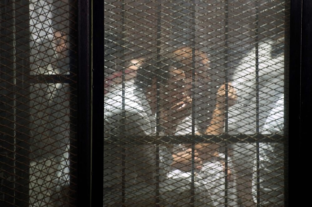 This picture shows detainees inside the soundproof glass dock of the courtroom during the trial of 700 defendants including Egyptian photojournalist Mahmoud Abu Zeid, widely known as Shawkan, in the capital Cairo, on September 8, 2018.  AFP / Mohamed el-S