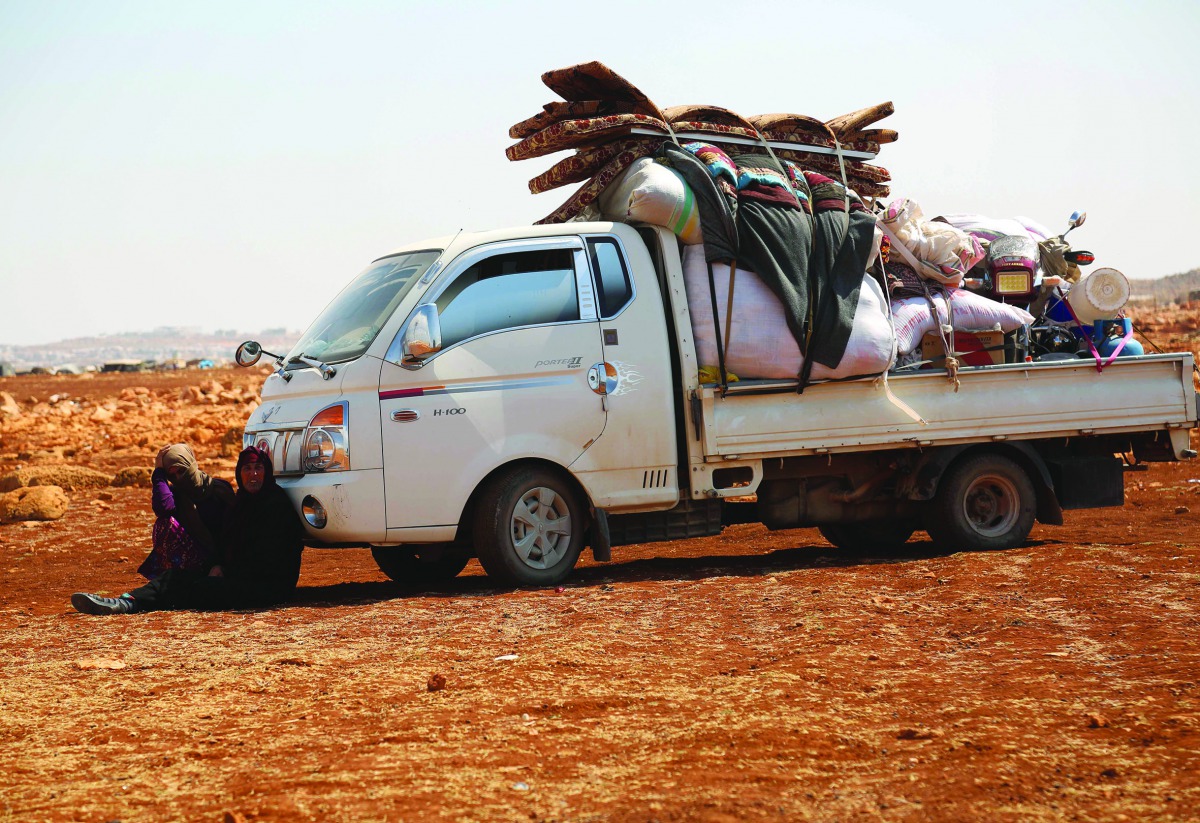 Displaced Syrians rest in the shade of a truck as they arrive with their belongings to a camp in Kafr Lusin near the border with Turkey in the northern part of Syria's rebel-held Idlib province on September 9, 2018.  AFP / Zein Al Rifai
