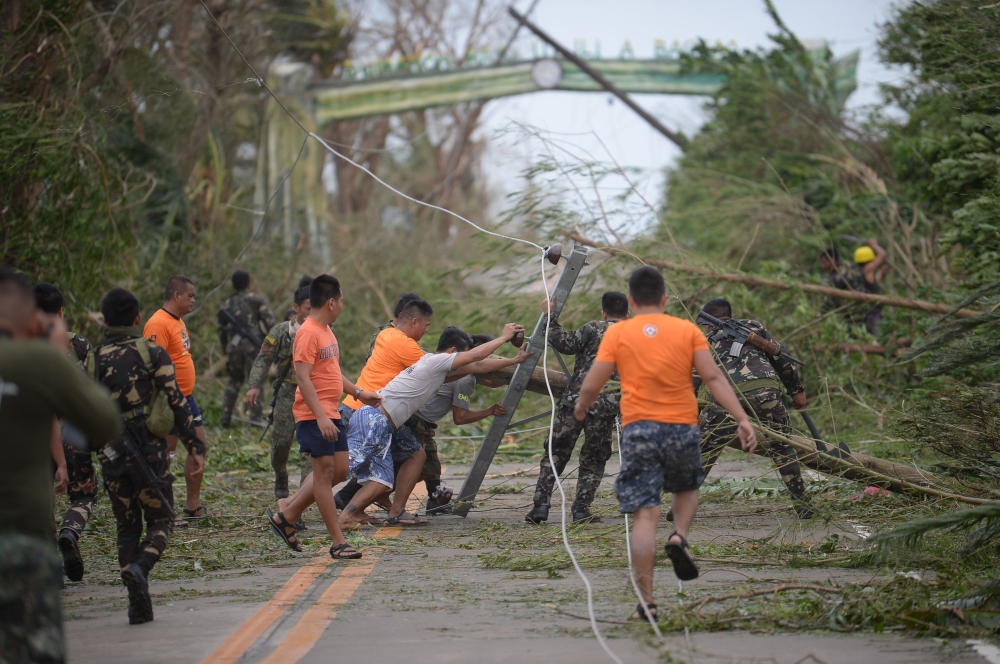 Rescue workers clear a road of debris and toppled electric posts caused by strong winds due to super Typhoon Mangkhut as they try to reach Baggao town in Cagayan province, north of Manila September 15, 2018. AFP / TED ALJIBE