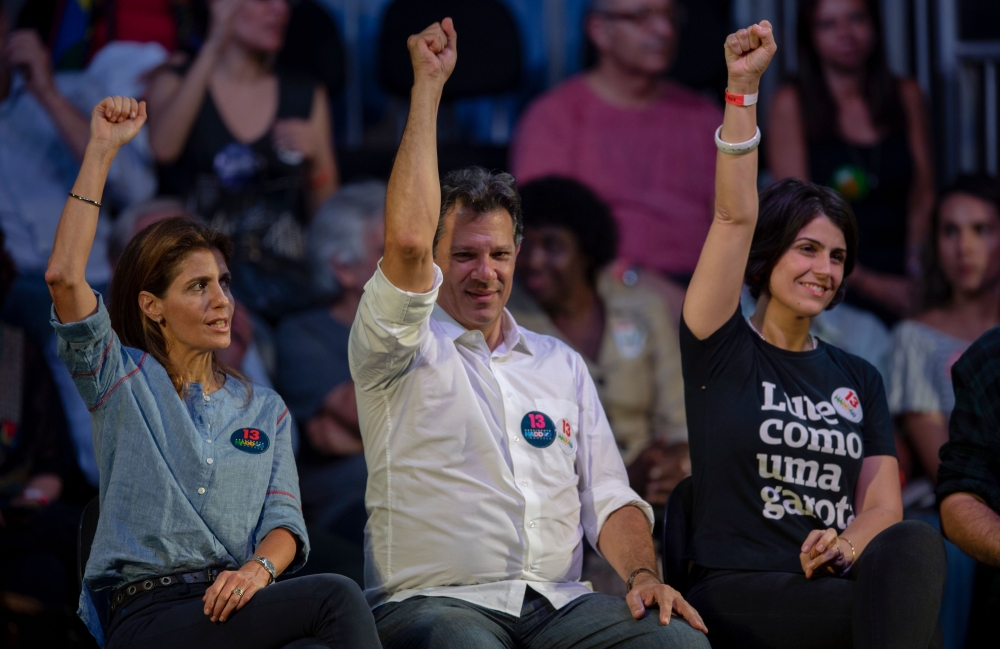 Brazilian presidential candidate for the Workers Party (PT), Fernando Haddad (C), his wife Ana Estela Haddad (L) and Brazilian vice presidential candidate Manuela D'Avila (R), lift their hands up during a campaign rally in Rio de Janeiro, Brazil on Octobe