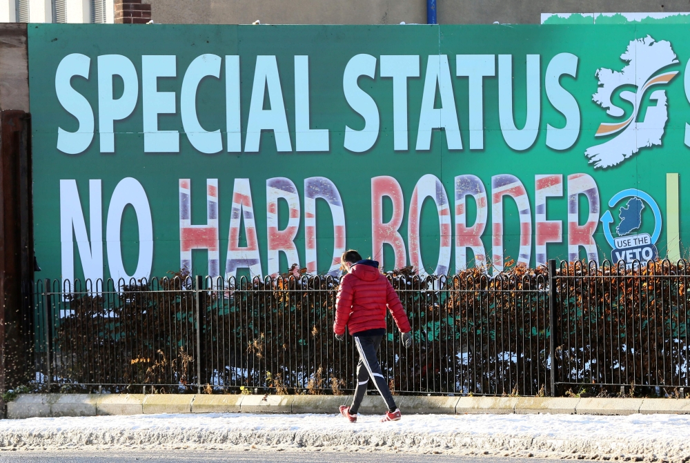 A man walks past a billboard in west Belfast erected by Republican Party Sinn Fein calling for a special status for northern Ireland with respect to Brexit and no hard borders in Ireland on December 08, 2017. AFP / Paul Faith 