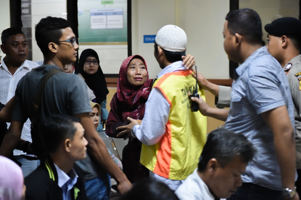 This picture taken on May 3, 2018 shows a woman (centre L) embracing her son after he and a group of young Indonesian men were found guilty of murdering 30-year-old Muhammad al-Zahra, at a court in Bekasi, West Java province. AFP/Bay Ismoyo