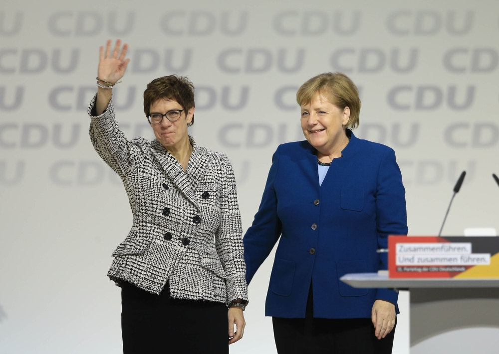 Annegret Kramp-Karrenbauer (L) greets delegates while she stands next to German Chancellor Angela Merkel (R) after Kramp-Karrenbauer has been elected as new party leader during the 31st Party Congress of the Christian Democratic Union (CDU) at a congress 