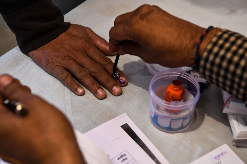 A polling officer marks a voters' finger with ink as he casts his vote at a local polling station during Rajasthan's Legislative Assembly election, in Jodhpur on December 7, 2018. / AFP / CHANDAN KHANNA 