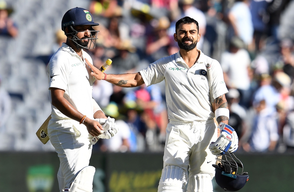 India's batsman Virat Kohli (R) greets his teammate Cheteshwar Pujara at the end of play on the day one of the third cricket Test match between Australia and India in Melbourne on December 26, 2018. AFP / WILLIAM WEST