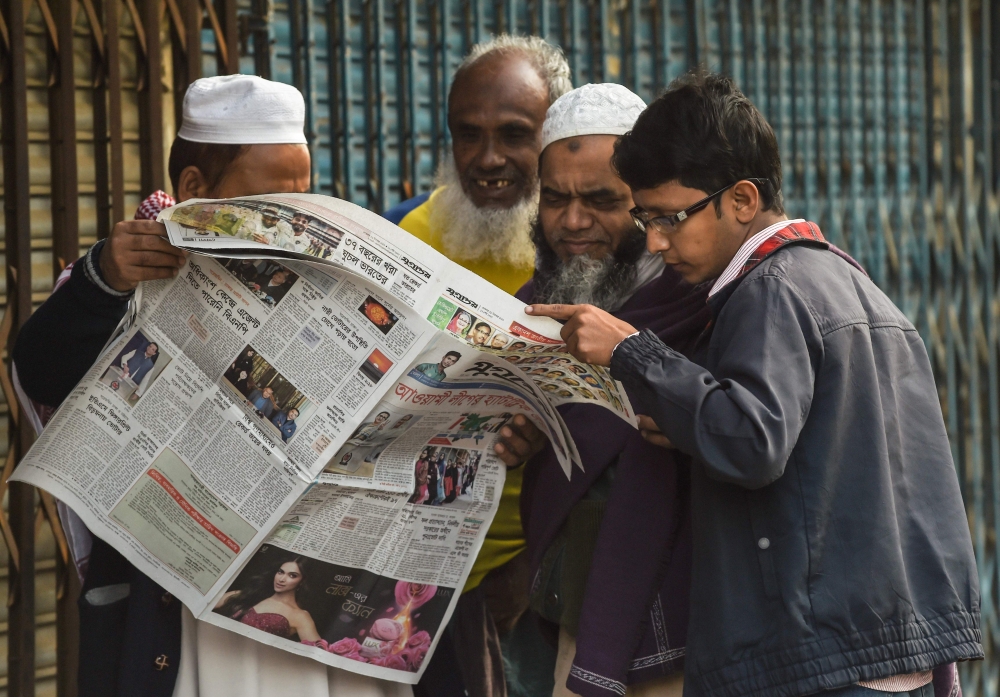 Bangladeshi people read a newspaper carrying headlines of the general election results in Dhaka on December 31, 2018. AFP / Indranil MUKHERJEE