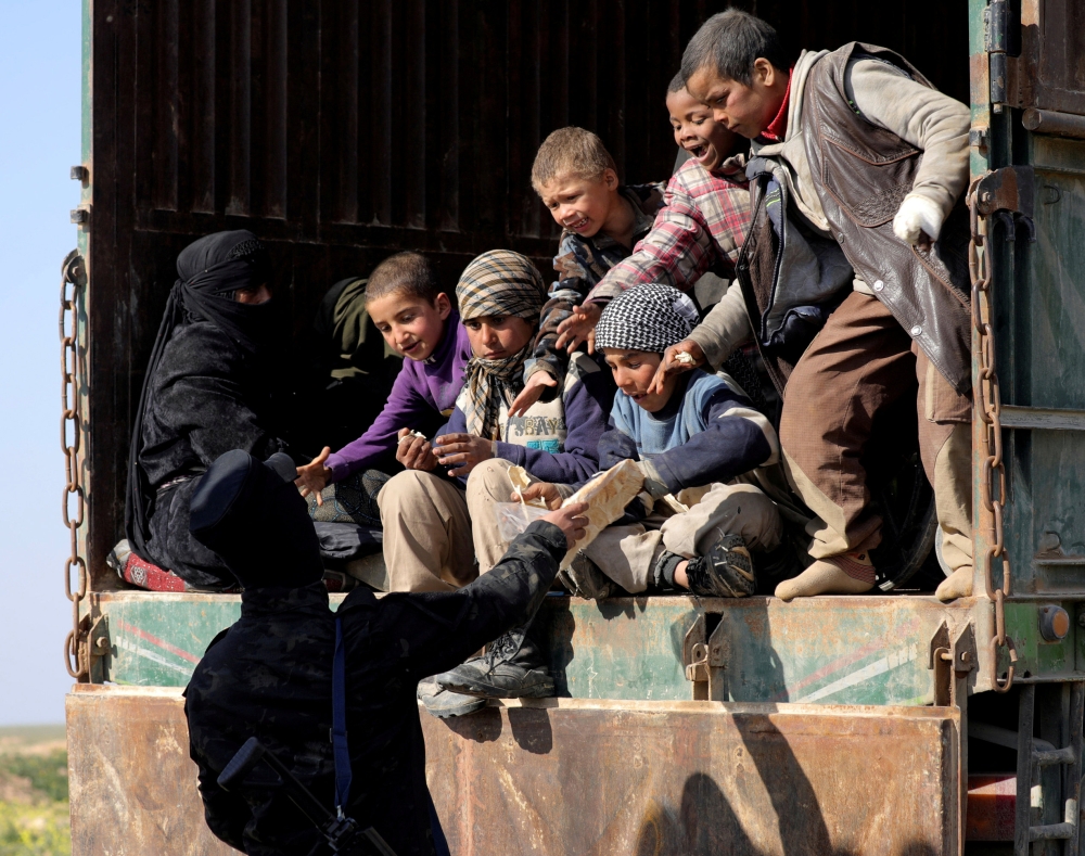 A fighter from the Syrian Democratic Forces (SDF) gives bread to children near the village of Baghouz, Deir Al Zor province, Syria February 20, 2019. REUTERS/Rodi Said