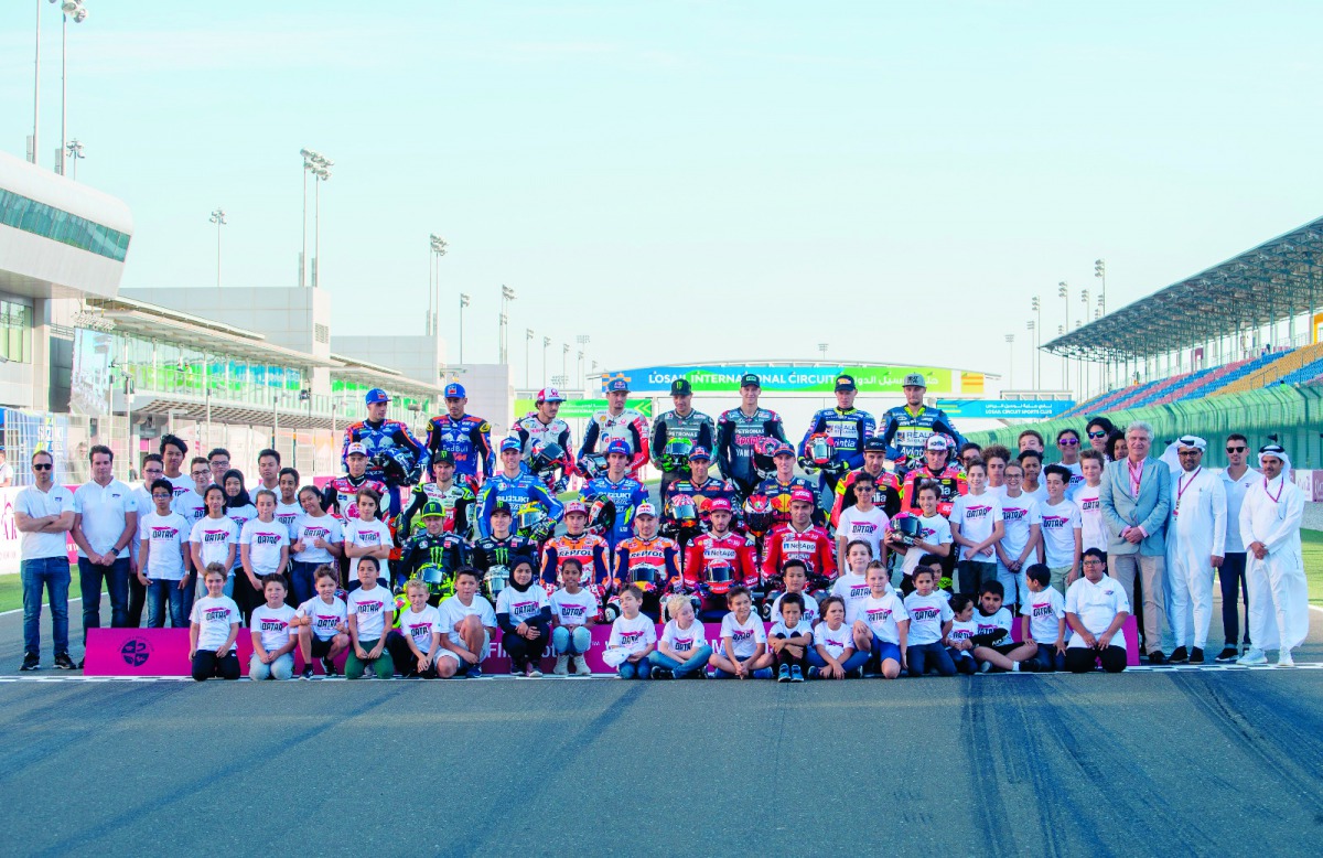 MotoGP riders, FIM and QMMF officials pose for a photograph with young Qatar Motor Academy riders at Losail International Circuit, yesterday.