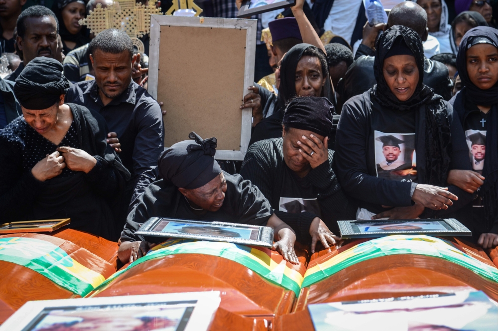 Mourners of victims of the crashed accident of Ethiopian Airlines react beside coffins during the mass funeral at Holy Trinity Cathedral in Addis Ababa, Ethiopia, on March 17, 2019. AFP / Samuel HABTAB