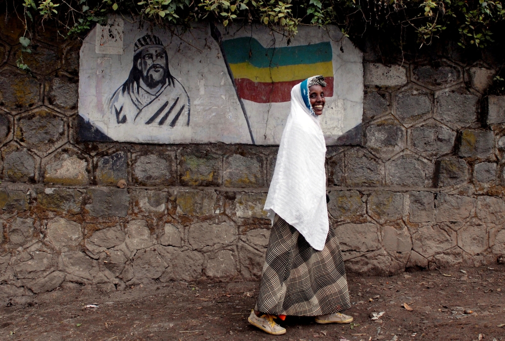 FILE PHOTO: A traditionally-dressed Ethiopian woman walks past a mural depicting Ethiopia's Emperor Tewodros II in Addis Ababa, Ethiopia, June 1, 2007. REUTERS/Andrew Heavens