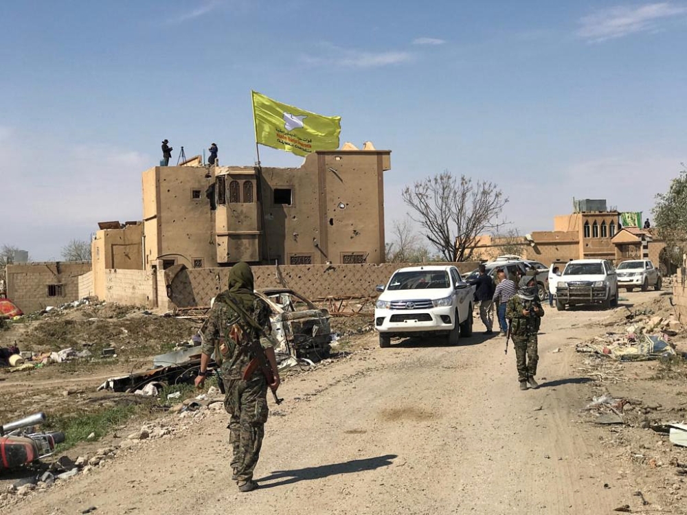 A Syrian Democratic Forces flag flutters on a damaged building in the village of Baghouz, Deir Al Zor province, Syria, March 23, 2019. REUTERS