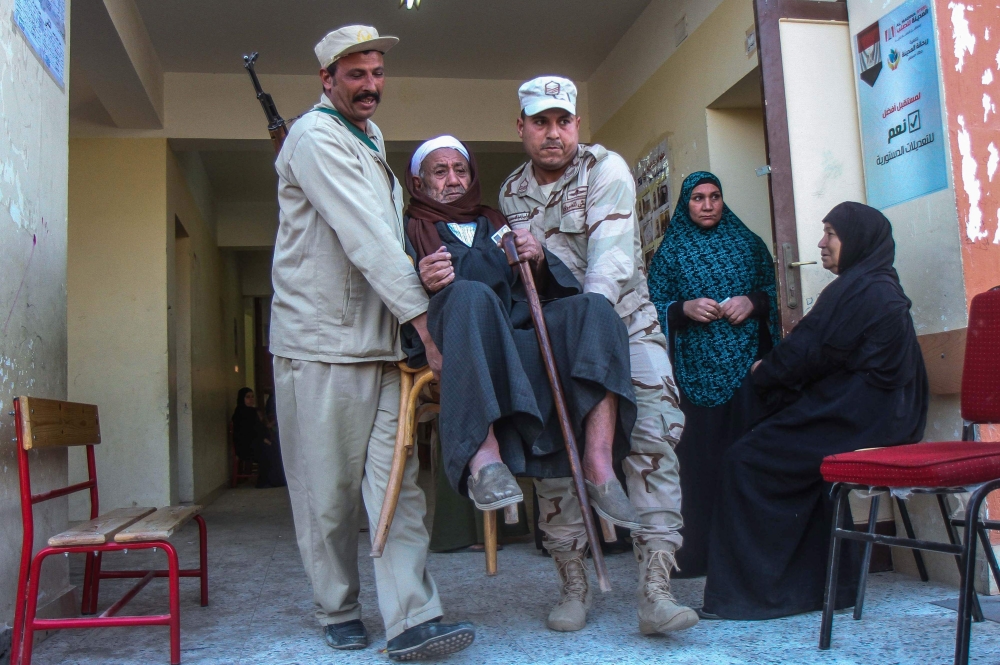 Egyptian soldiers carry an elderly man at a polling station in a referendum on constitutional amendments, at a school in al-Ayat village, 90 km south of Cairo, on the first day of a three-day poll, on April 20, 2019. AFP