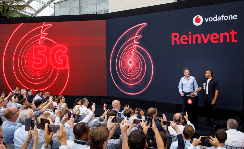 Vodafone UK CEO, Nick Jeffery (L) and British Formula One racing car driver Lewis Hamilton attend the launch of Vodafone UK's 5G mobile data network in London on July 3, 2019. AFP / Tolga Akmen
 