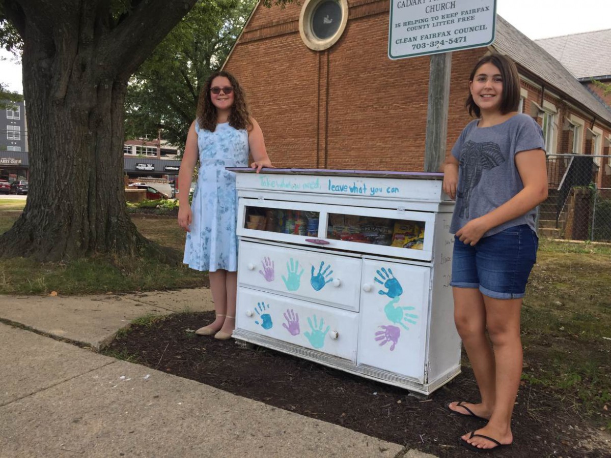 Amanda Santana (L) and Anna Rissi stand with their Little Free Pantry project in Alexandria, Virginia, in September 2019. Thomson Reuters Foundation/Carey L. Biron