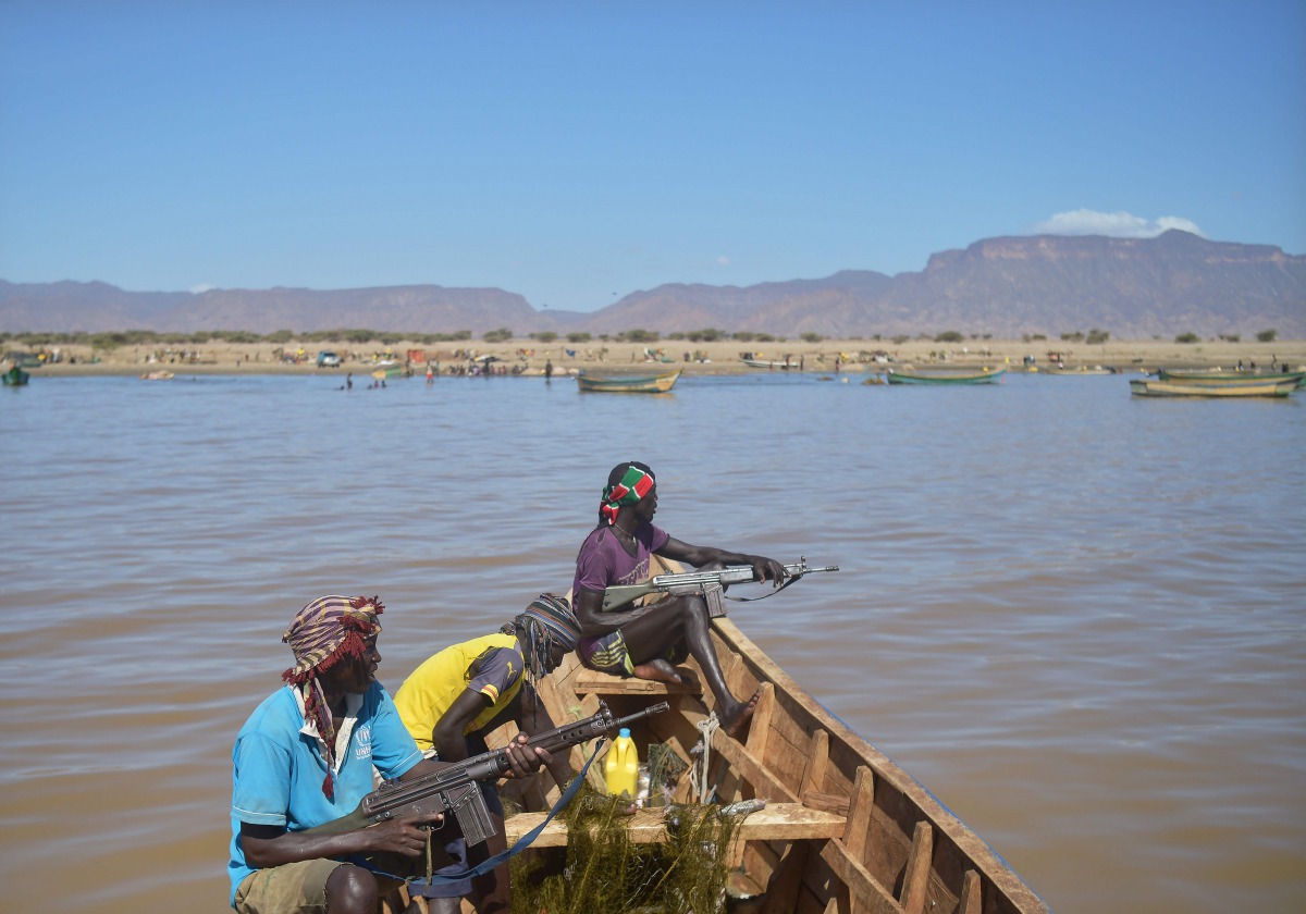 Armed fishermen return from a fishing expedition aboard a boat on March 24, 2017 near Lowarengak, on the western shores of Lake Turkana, northern Kenya. AFP / Tony Karumba