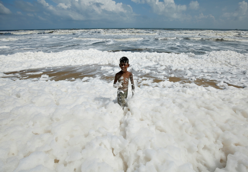 A boy plays with foam formed from pollution at the Marina beach in Chennai, India, November 29, 2019. REUTERS/P. Ravikumar
