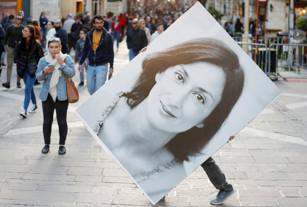 A person walks with a picture of Daphne Caruana Galizia during a demonstration to demand justice over the murder of the journalist, in Valletta, Malta, December 1, 2019. Reuters/Yara Nardi 