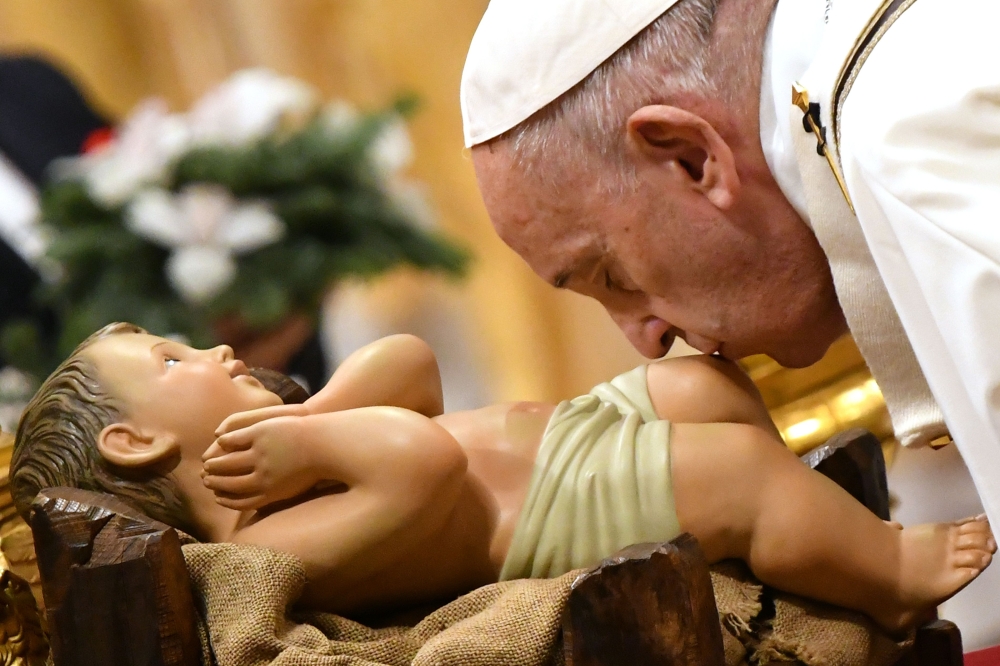 Pope Francis kisses a figurine of baby Jesus during a mass on Christmas eve on December 24, 2019, at St Peter's basilica in the Vatican. AFP / Alberto Pizzoli 