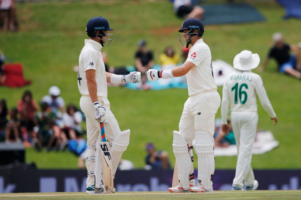England's Joe Denly (L) and England's Joe Root (R) greet each other during the fourth day of the first Test cricket match between South Africa and England at The SuperSport Park stadium at Centurion near Pretoria on December 29, 2019. / AFP / MARCO LONGAR