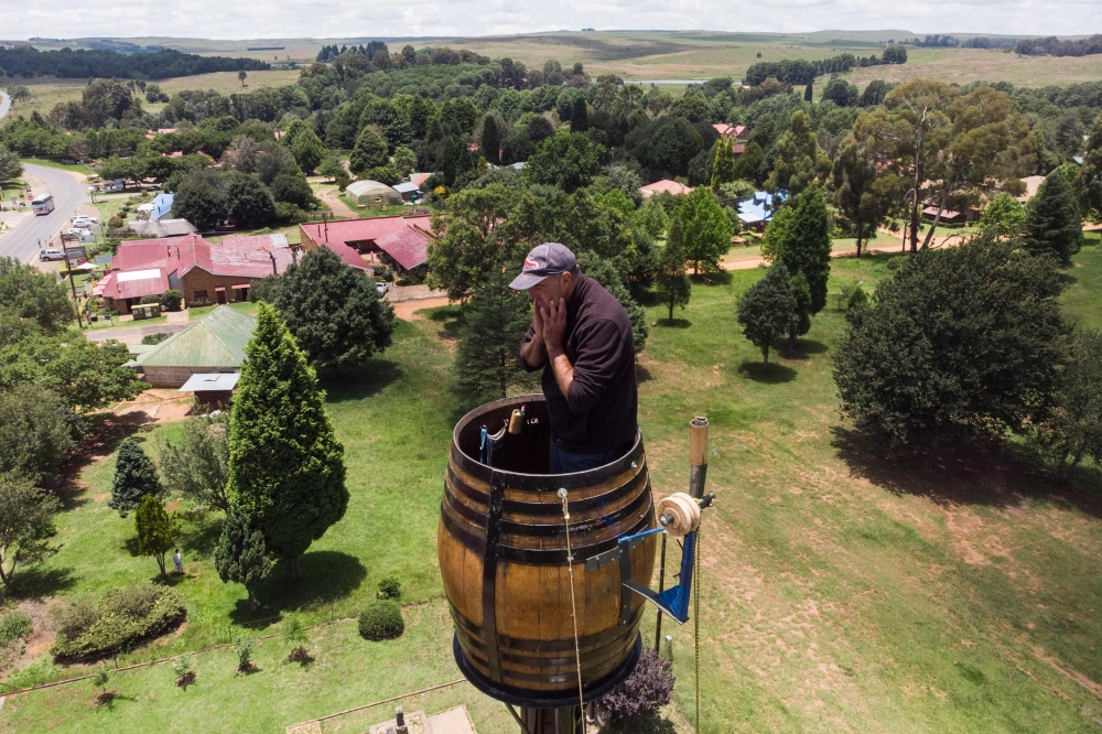 An areal view shows Vernon Kruger, 52, holding his face while standing in a barrel at the top of a pole 25 metres above the ground in Dullstroom on January 16, 2020. AFP / Antoine Demaison 