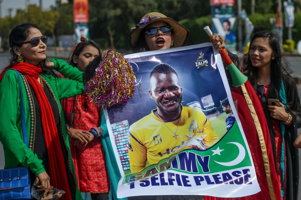  Spectators carry a poster featuring an image of Peshawar Zalmi's team captain Darren Sammy outside the National Cricket Stadium in Karachi on February 21, 2020, ahead of the start of the Pakistan Super League (PSL) T20 cricket match between Peshawar Zalm