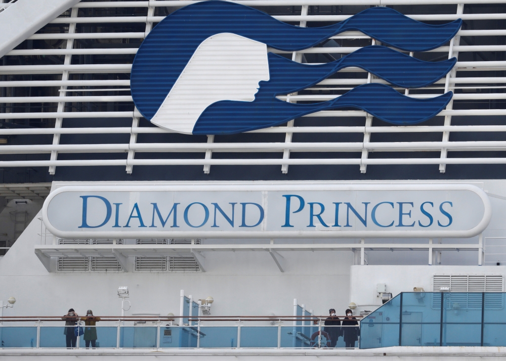 FILE PICTURE: Masked passengers look on from on board the coronavirus-hit Diamond Princess cruise ship docked at Yokohama Port, south of Tokyo, Japan, February 20, 2020. REUTERS/Kim Kyung-Hoon/File Photo
 