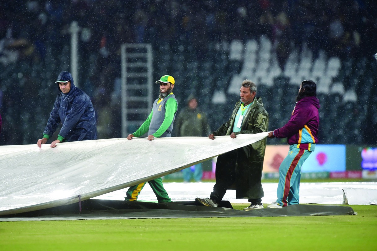 Ground staff members cover the pitch during rain showers during the Pakistan Super League (PSL) T20 cricket match between Karachi Kings and Multan Sultans at the Gaddafi Cricket Stadium in Lahore on March 6, 2020. AFP / Arif Ali
