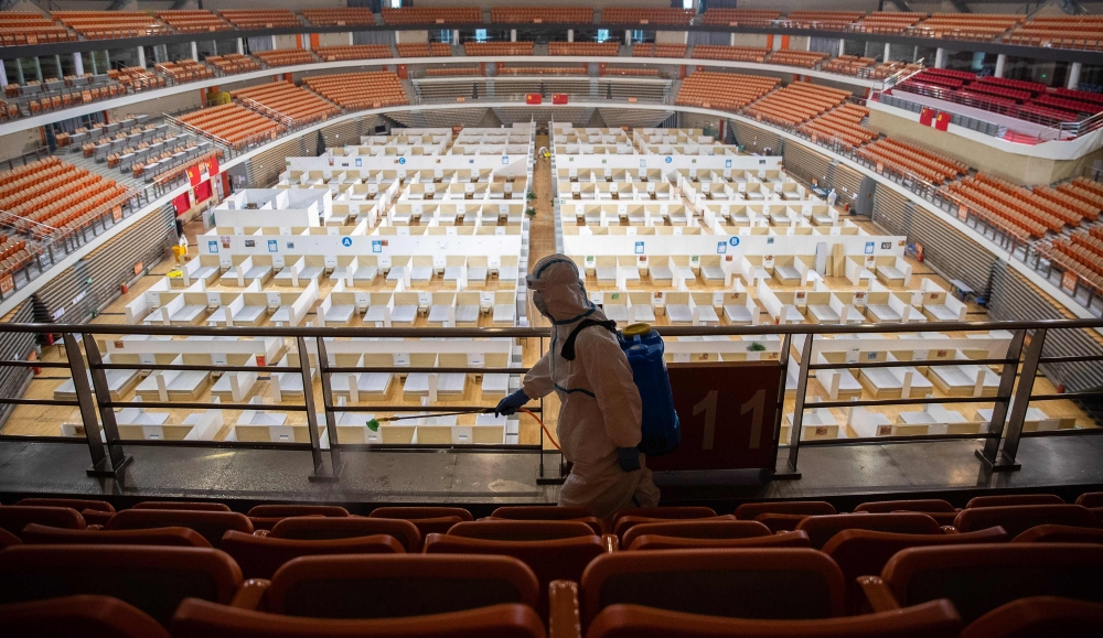 A staff member sprays disinfectant after the final patients were discharged at a temporary hospital set up to treat people with the COVID-19 coronavirus in a sports stadium in Wuhan, in China's central Hubei province on March 8, 2020.  / AFP / STR AND STR