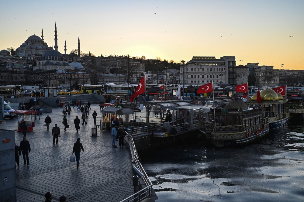 People walk past a nearly empty square at Eminonu as the nation tries to contain the novel coronavirus, COVID-19, in Istanbul on March 17,2020 . / AFP / Ozan KOSE