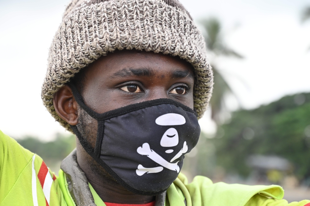 A man wearing a face mask as a preventive measure against the spread of the COVID-19 coronavirus directs traffic on a road in Abobo, in the suburbs of Abidjan on March 21, 2020.   AFP / ISSOUF SANOGO
