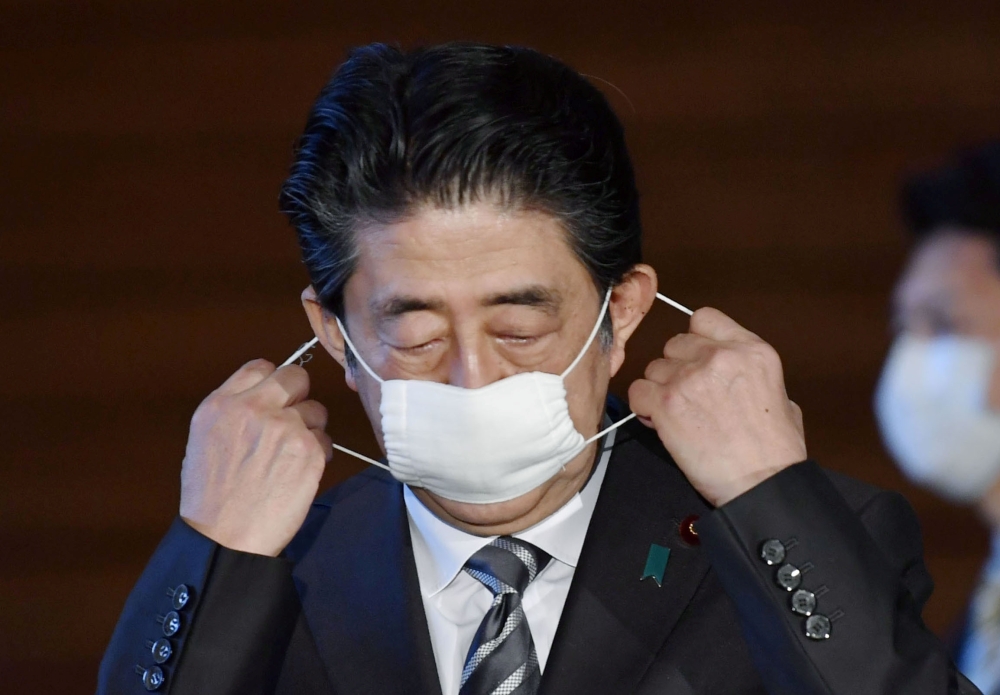 Japan's Prime Minister Shinzo Abe puts off his protective face mask as he speaks to media on Japan's response to the coronavirus disease (COVID-19) outbreak at his official residence in Tokyo, Japan, May 1, 2020, in this photo taken by Kyodo. 