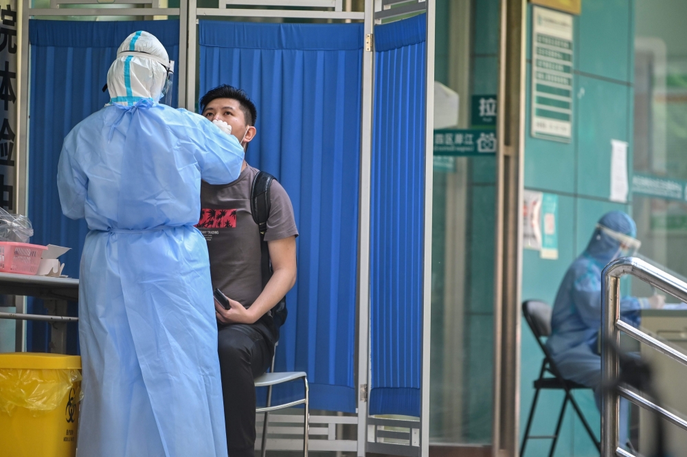 :A medical worker takes a swab sample from a man to be tested for the COVID-19 novel coronavirus in Wuhan, in China’s central Hubei province on May 13, 2020. Wuhan plans to conduct coronavirus tests on the Chinese city's entire population after new cases 
