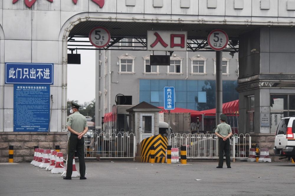 Chinese paramilitary police officers guard an entrance to the closed Xinfadi market in Beijing on June 13, 2020. AFP / GREG BAKER
