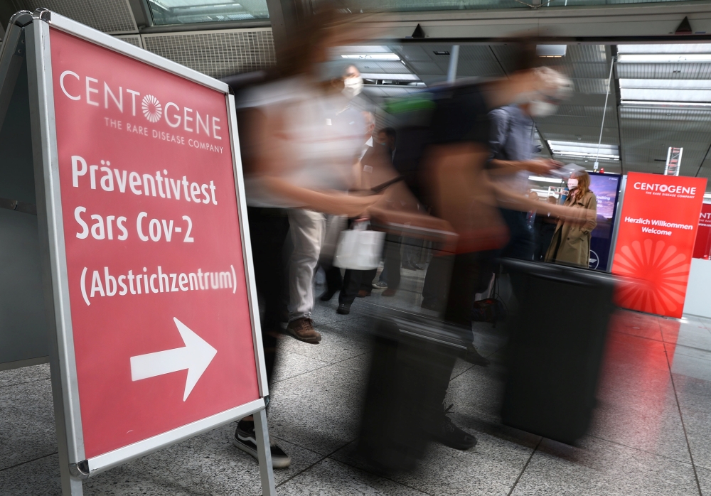 Travellers rush past the entry of Germany's first walk-through the coronavirus disease (COVID-19) test center which is opened by diagnostics provider Centogene in cooperation with air carrier Lufthansa and Fraport at the airport in Frankfurt, Germany June