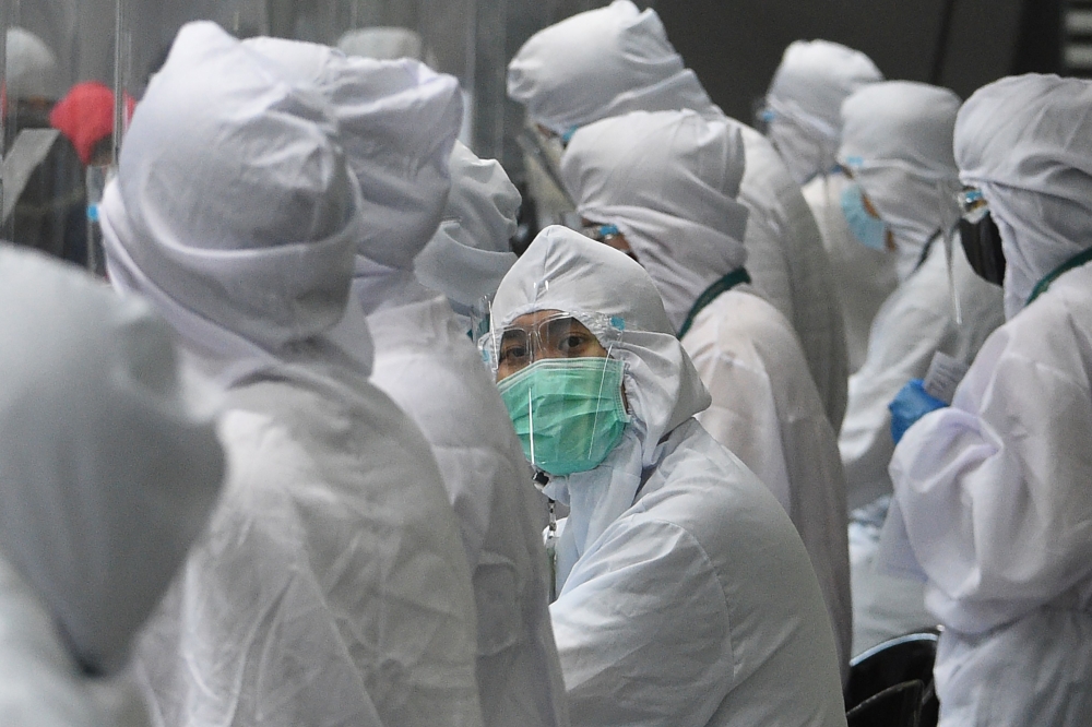 Airline ground staff wearing protective gear work at the counter at the airport in Manila on August 4, 2020. More than 27 million people -- a quarter of the Philippine population -- were give 24-hours notice of the new restrictions that have shuttered man