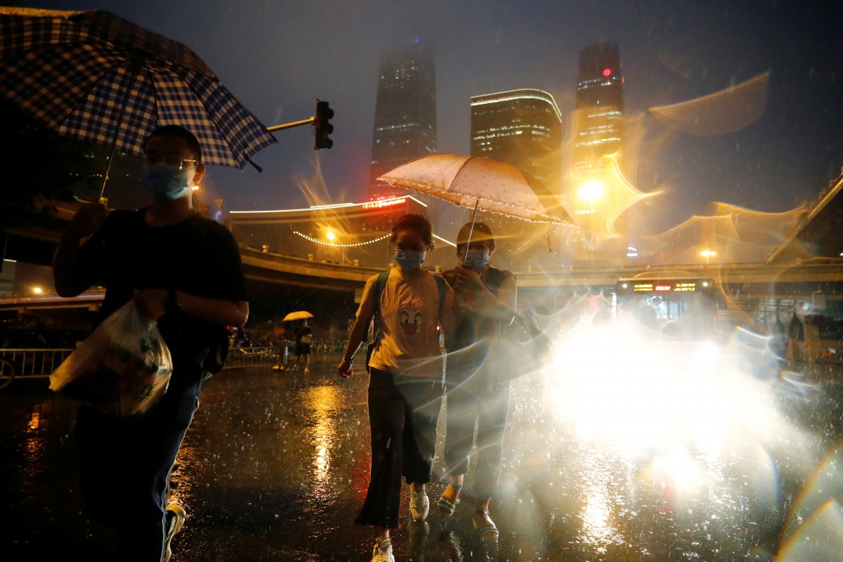 People carry umbrellas on a rainy day following an outbreak of the coronavirus disease (COVID-19) in Beijing, China August 12, 2020. REUTERS/Thomas Peter