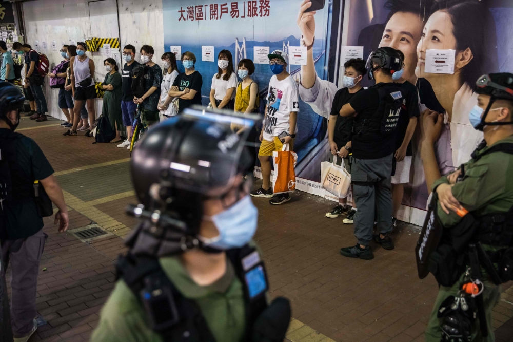 Police question a group of people as they patrol the area after protesters called for a rally in Hong Kong on September 6, 2020 to protest against the government's decision to postpone the legislative council election due to the COVID-19 coronavirus, and 