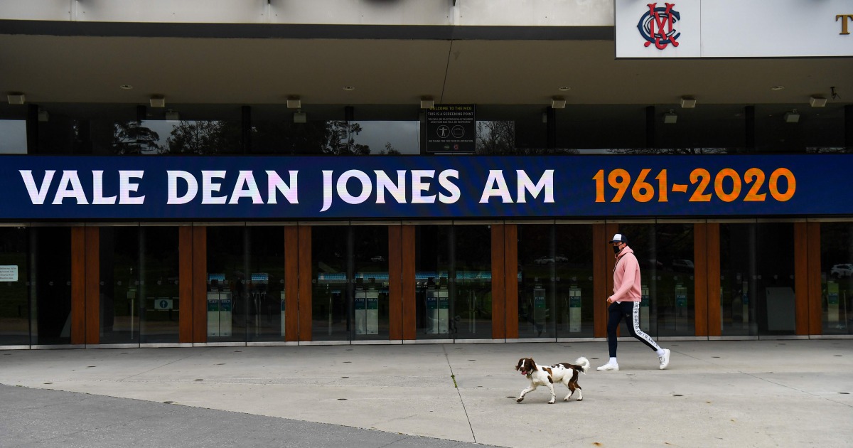 A pedestrian walks past a sign at the Melbourne Cricket Ground (MCG) remembering former Australian Cricketer Dean Jones in Melbourne on September 25, 2020 after he died the day before aged 59. / AFP / William WEST
