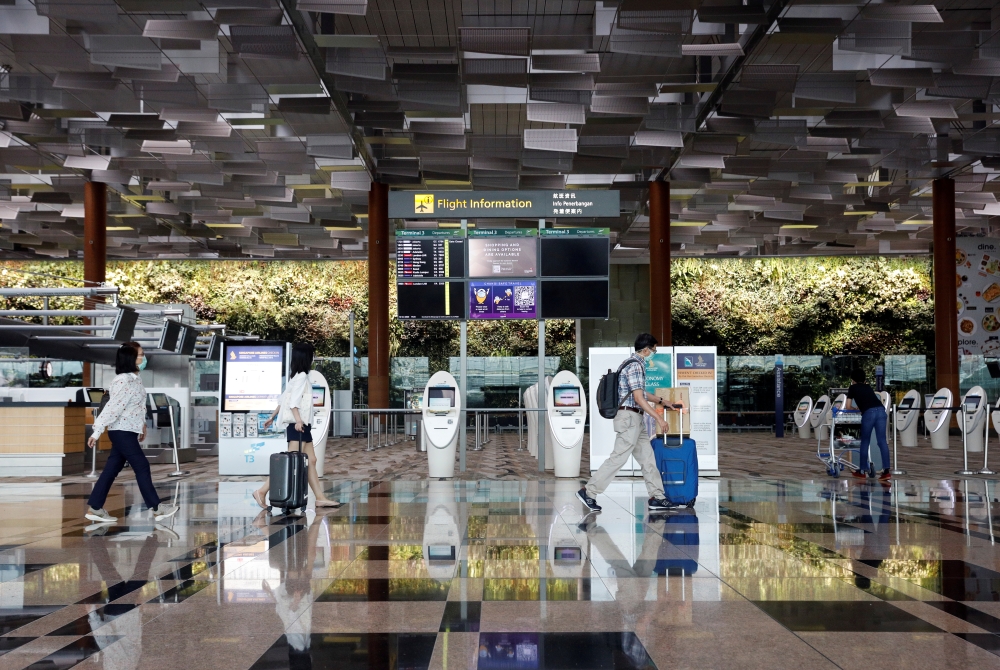 People wearing protective face masks walk past self check-in machines, amid the spread of the coronavirus disease (COVID-19) at the Changi Airport in Singapore October 12, 2020. REUTERS/Edgar Su