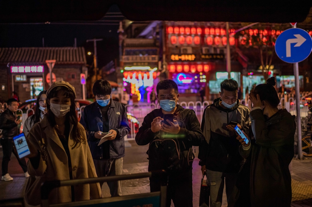 People wearing face masks as a preventive measure against the Covid-19 show a QR code 