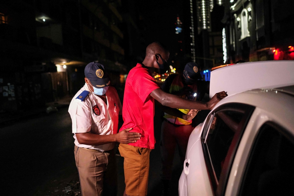 A Johannesburg Metro Police Department (JMPD) officer frisks a driver during a roadblock after curfew, to help curb the spread of COVID-19, in Johannesburg on December 29, 2020. AFP / Wikus de Wet